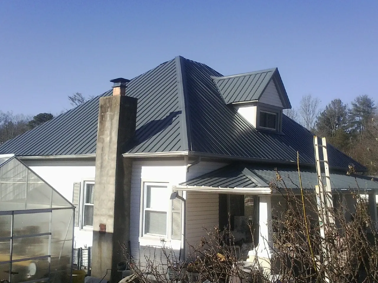 Dark blue standing seam metal roof on a white farmhouse with dormer — Slate & Tile Roof Repair by Roofing Brothers in East Prospect