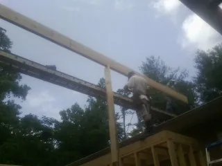 Carpenter setting a ridge beam over a new addition frame — Ice Dam Removal by Roofing Brothers in East Prospect