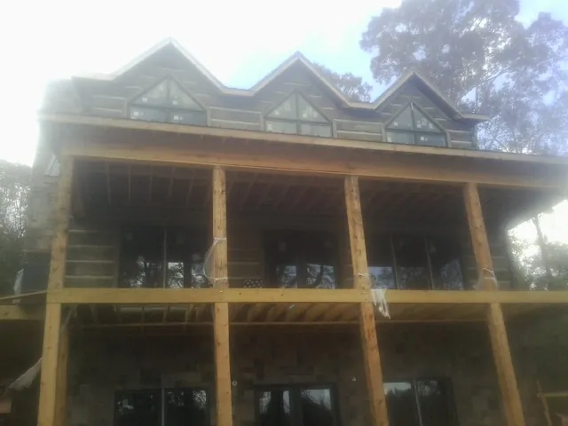 Dormers and porch framing on a large log home under construction — Roof Coating work by our crew in East Prospect