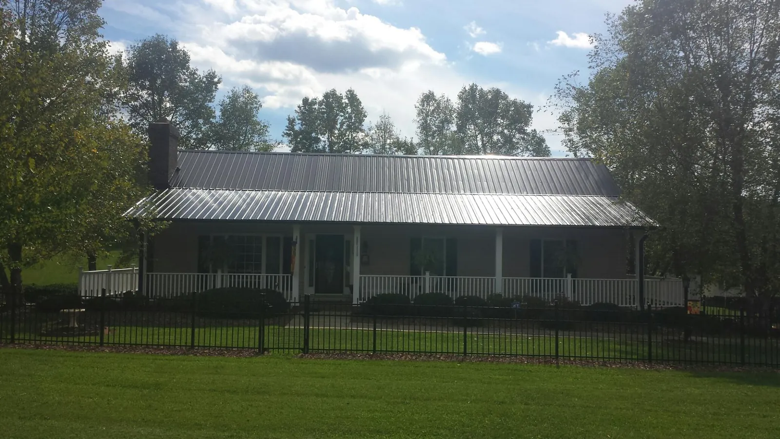 Gray metal roof on a brick ranch with a full width front porch — Gutter Guard Installation work by our crew in East Prospect