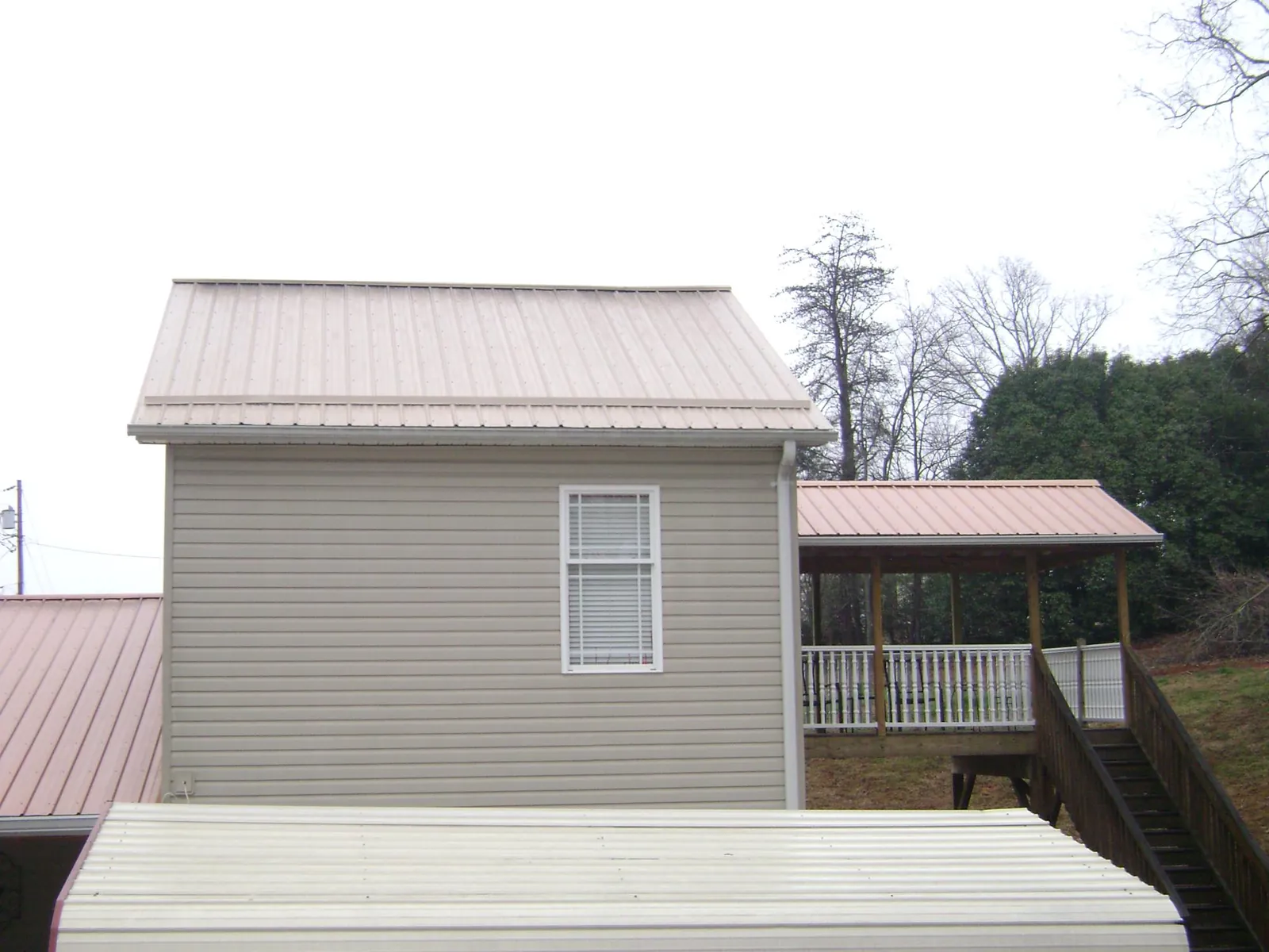 Tan metal roofs on a two story addition and attached porch, from a Roof Replacement job in East Prospect